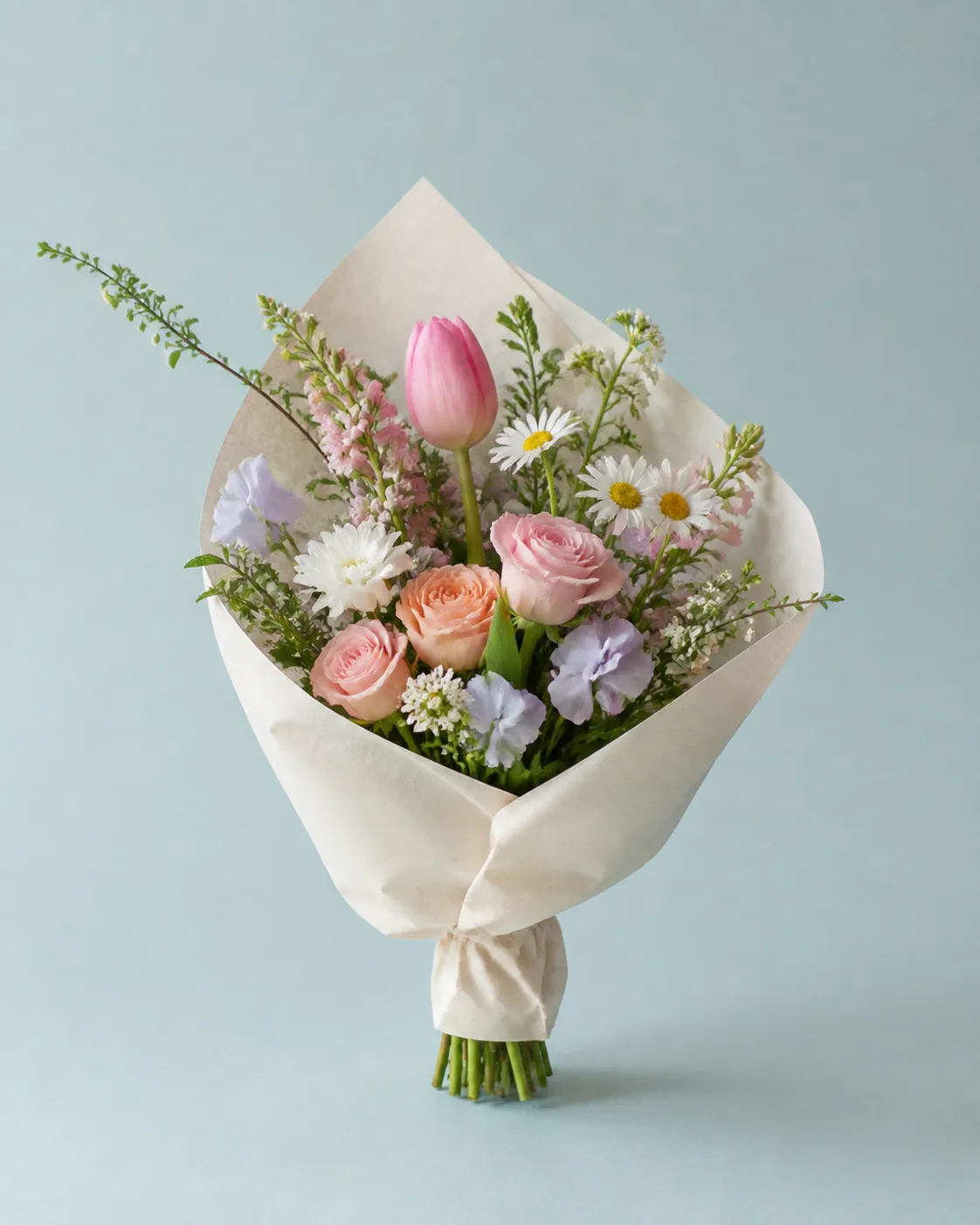 A petite mixed-pastel bouquet of roses, tulip, daisies and greenery