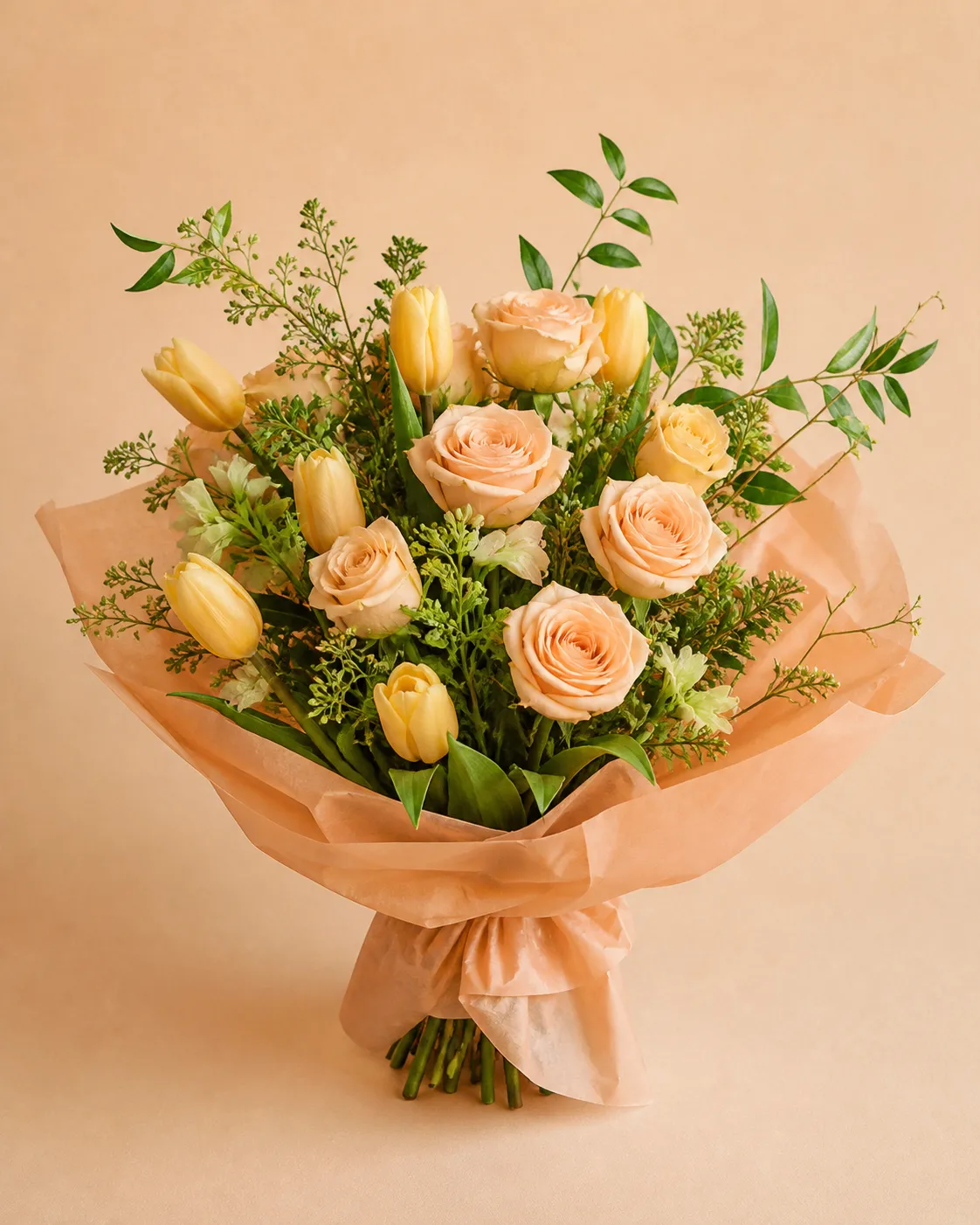 Peach roses and yellow tulips with green foliage in the Peach Light bouquet